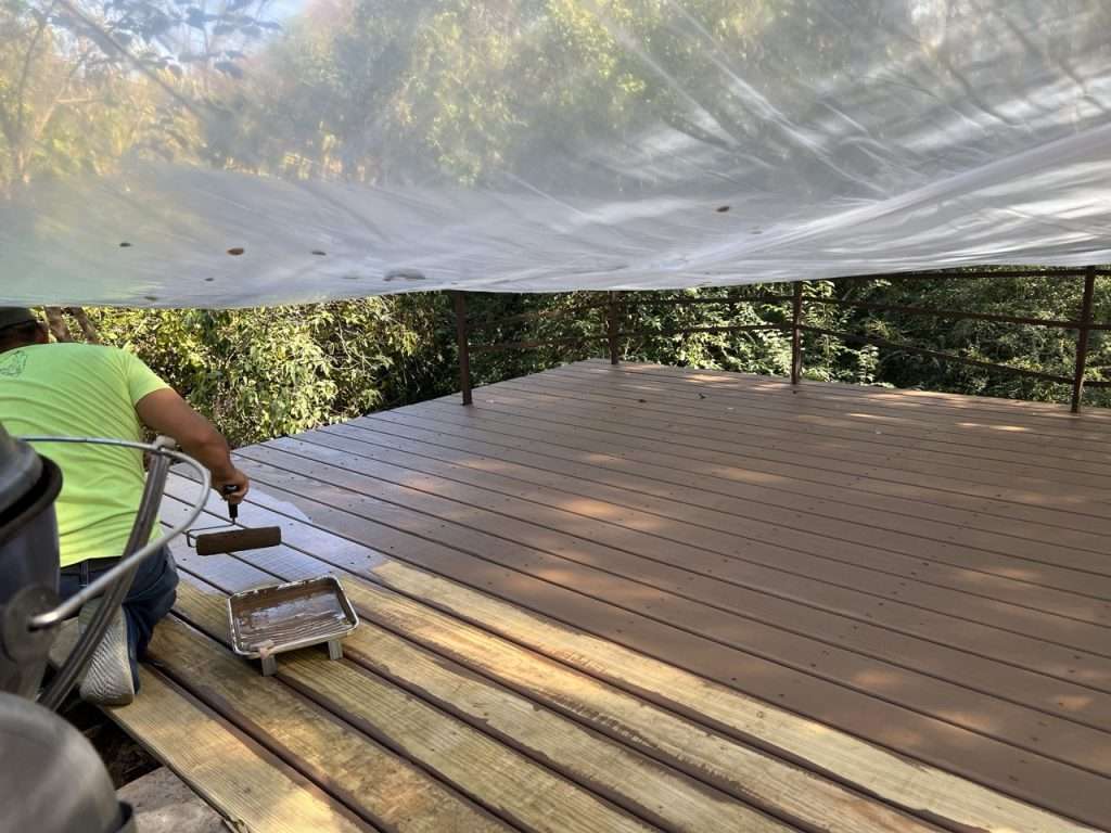 rolling stain onto pressure treated deck boards during backyard deck project in Dallas