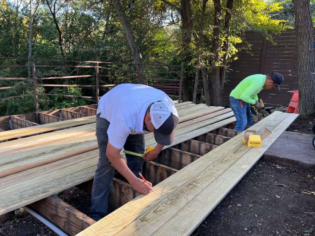 contractors measuring and installing deck boards during Dallas backyard deck construction