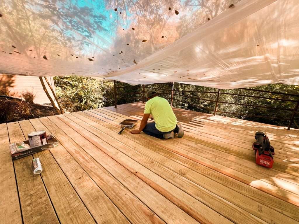 contractor staining newly installed backyard deck boards during Dallas deck installation