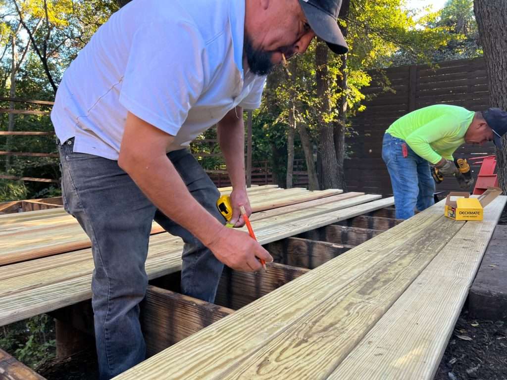 installing pressure treated deck boards on elevated backyard deck frame