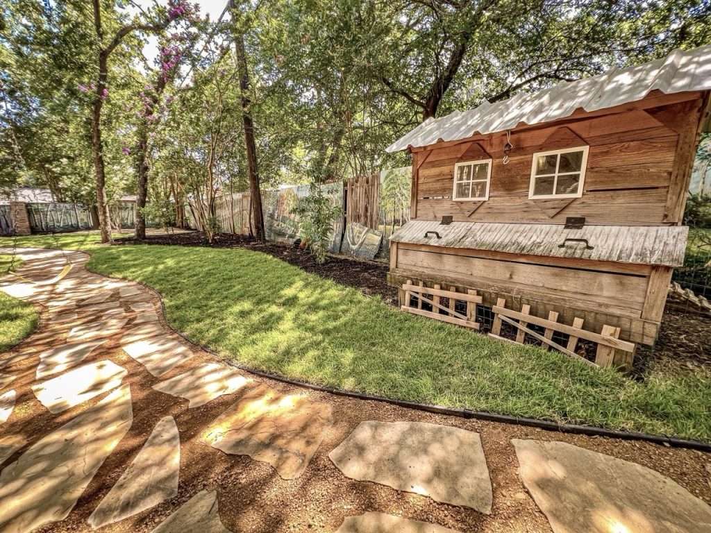 Completed Dallas backyard landscape renovation with curved flagstone walkways, new lawn, and mature shade trees